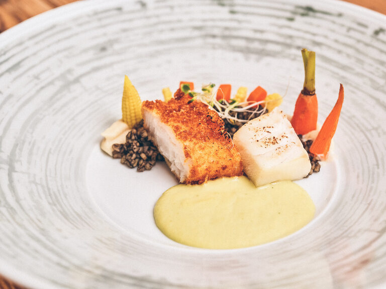 Fischgericht garniert mit Karotten, Soße und Mais aus dem Restaurant Hotel Eibl-Brunner.