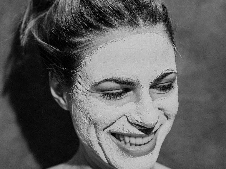 Aufnahme des Gesichts einer glücklichen Frau die eine Wellnessanwendung mit Gesichtsmaske im Wald Spa genießt. schwarz-weiss