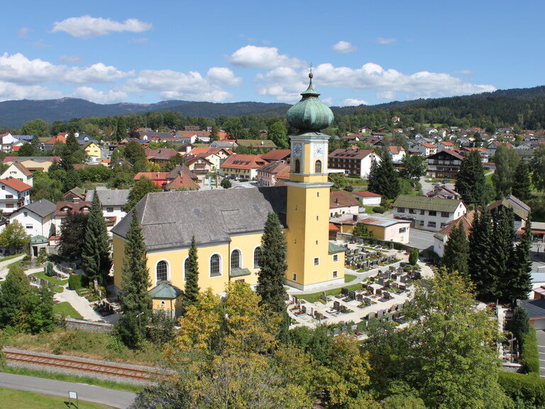 "Mariä Himmelfahrt" Kirche in Frauenau mit Friedhof und Blick in den Ort.