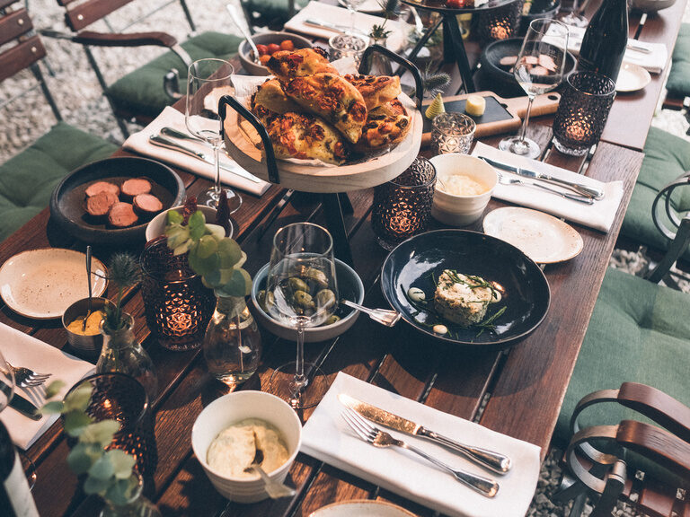 Verschiedene mediterrane Speisen auf einem schön gedeckten Tisch im Restaurantgarten des Hotel Eibl-Brunner.