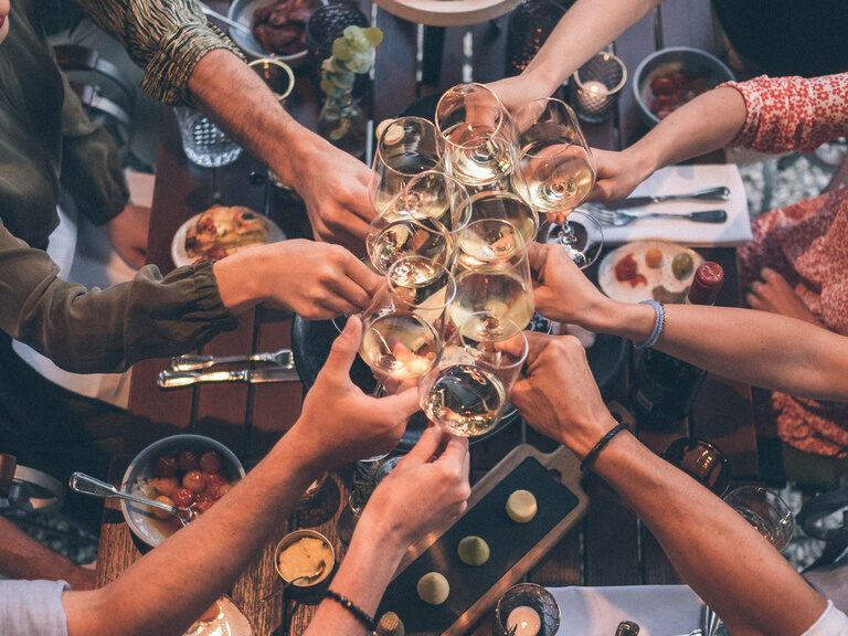 Gäste stoßen mit einem Glas Weisswein auf ein gelungenes Essen im Hotelgarten des Wellnesshotel Eibl-Brunner an.