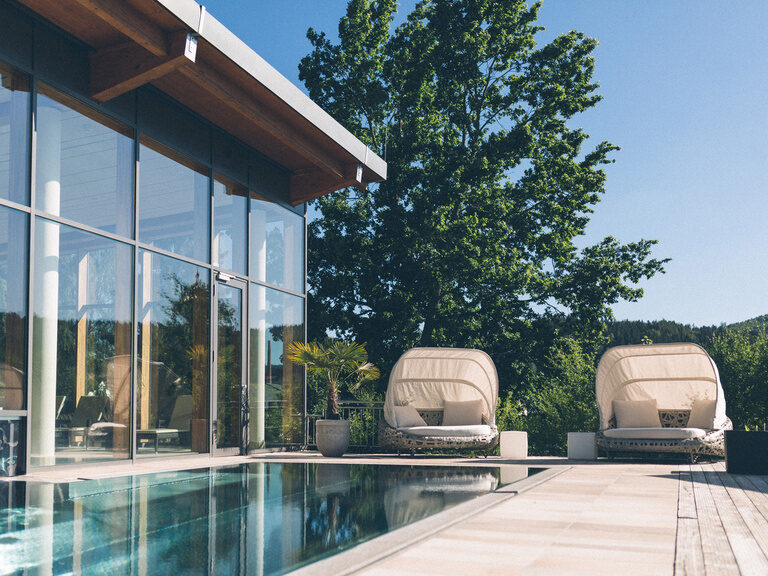 Der Außenpool im Sommer mit Sitzgelegenheiten um den Pool des Hotel Eibl-Brunner.