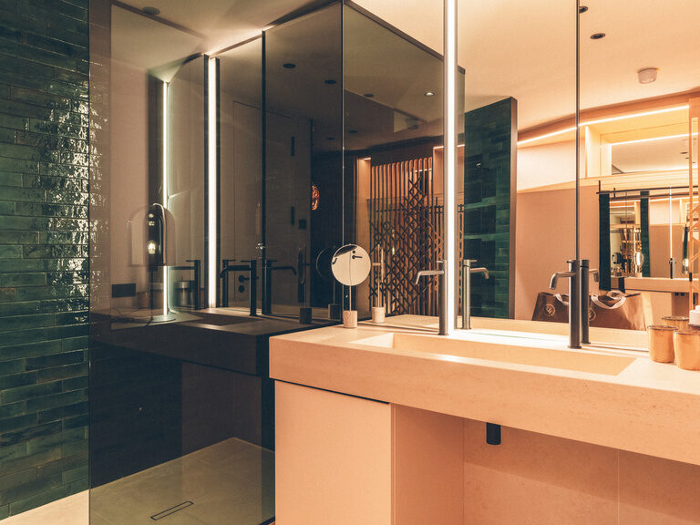 Helles Badezimmer mit begehbarer Dusche und großen Waschtisch mit Spiegel in der Wald Spa Suite des Hotel Eibl-Brunner.