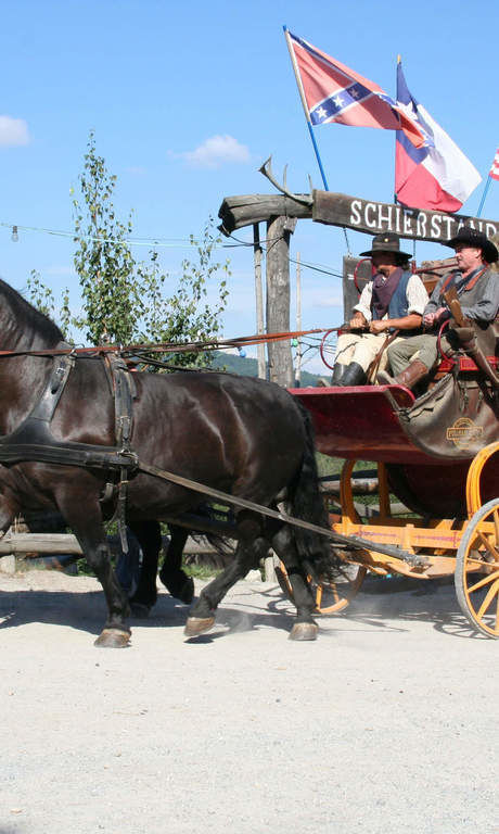 Eine Pferdekutsche die durch die Westernstadt Pullmann City, bei Eging am See fährt und eine der vielen weiteren Attraktionen in der belebten Westernstadt ist.