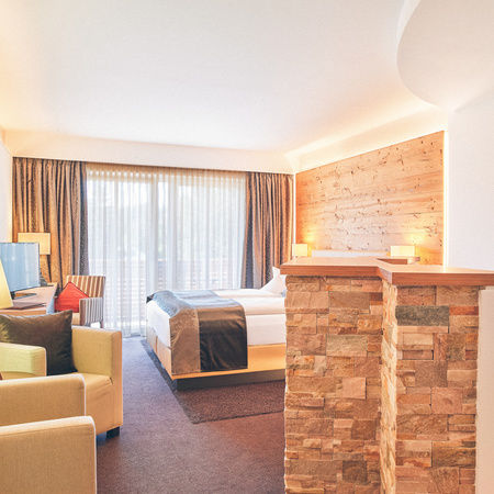 Doppelzimmer Arber im Hotel Eibl-Brunner - Blickrichtung Balkon mit Sitzgelegenheit und Doppelbett im Blick.