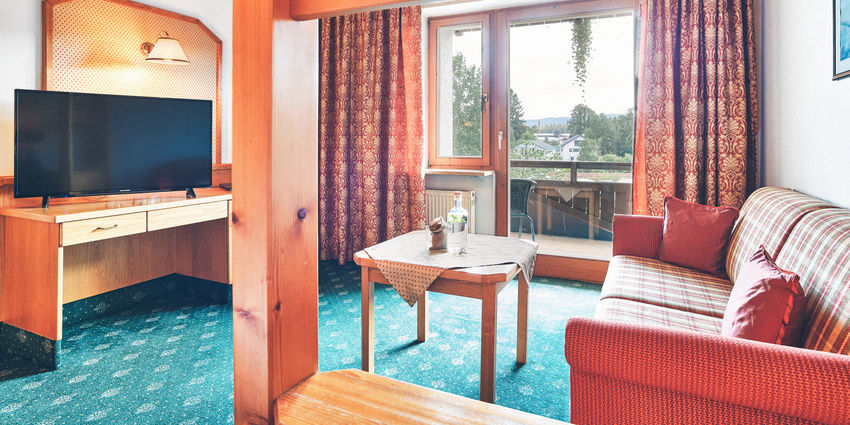 Gemütlich eingerichtetes Doppelzimmer im Stammhaus des Hotel Eibl-Brunner. Sitzgelegenheit mit Blick auf den Fernseher oder aus dem Balkonfenster.