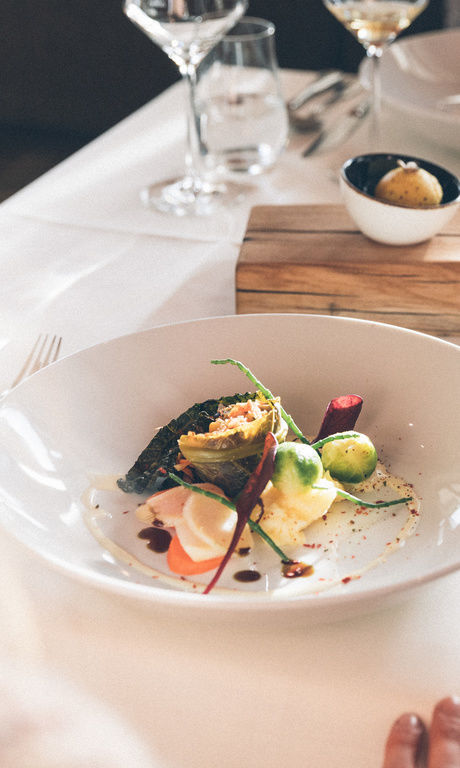 Ein für mehrere Gänge gedeckter Tisch, mit Weingläsern, Besteck und Brot mit Butter, im Restaurant Hotel Eibl-Brunner.