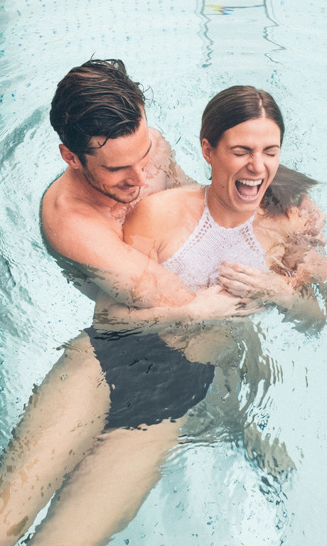 Ein Paar lacht und hat viel Spaß im Wasser des Hotelpools des Wellnesshotel Eibl-Brunner.