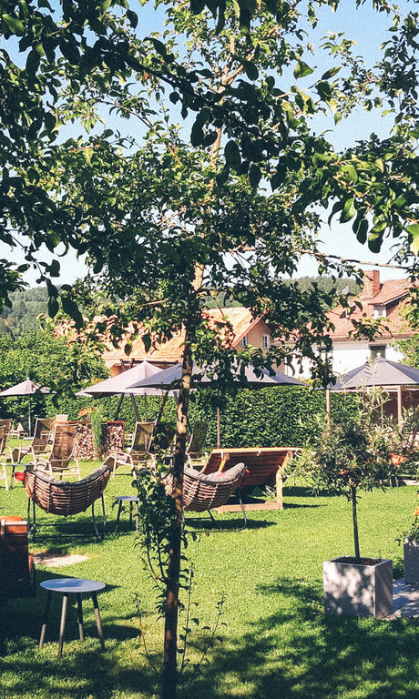 Der Hotelgarten ist mit Stühlen, Liegen, Bänken und Sonnenschirmen, um für die Gäste eine gemütliche Atmosphäre zu schaffen.