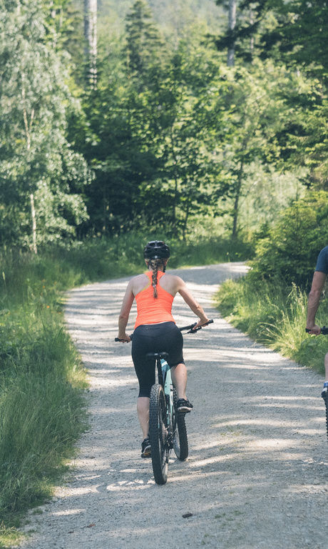 Zwei Radfahrer - zwei Gäste des Hotel Eibl-Brunner fahren durch den saftig grünen Wald in der Nähe des Hotels.