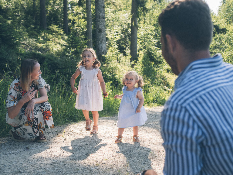Spielende Kinder auf einem Feldweg im Wald - die Eltern Diana und Stefan schauen ihnen zu.