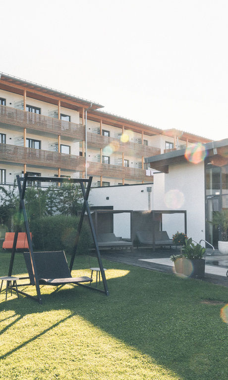 Hotelgarten mit Sonnenliegen und gemütlicher Hollywoodschaukel im Sommer.