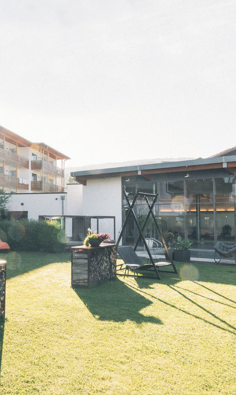 Sonnengefluteter Garten mit Sonnenliegen und Hollywoodschaukeln, neben dem Außenpool des Hotel Eibl-Brunner.