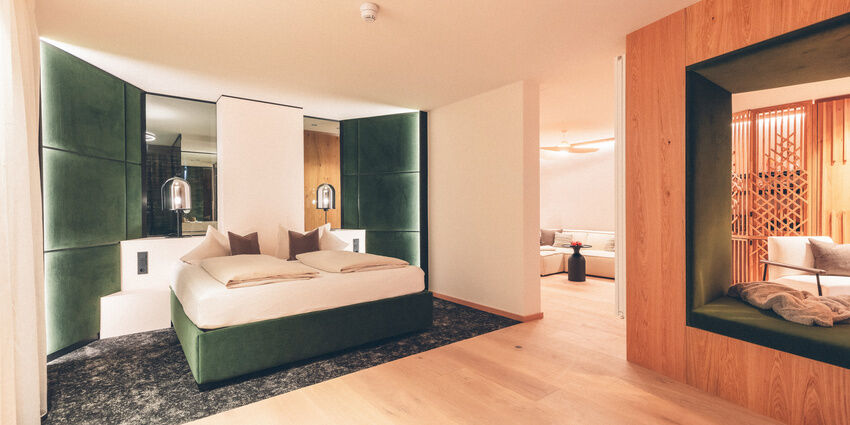 Hotel Doppelzimmer mit Leseecke und grünem Bett im Hotel Eibl-Brunner.