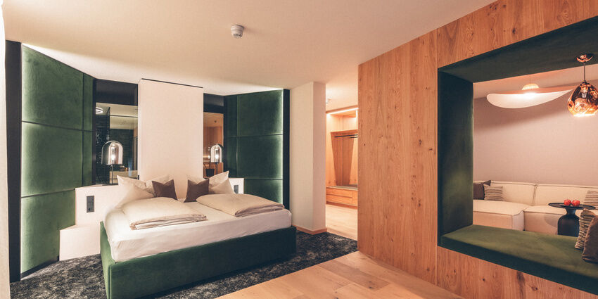 Grünes Doppelbett mit Zugang zur gemütlichen Leseecke / Sitzlounge in der Wald Spa Suite-73 im Hotel Eibl-Brunner.