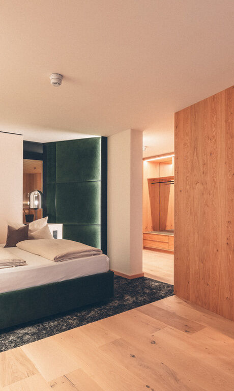 Grünes Doppelbett mit Zugang zur gemütlichen Leseecke / Sitzlounge in der Wald Spa Suite-73 im Hotel Eibl-Brunner.