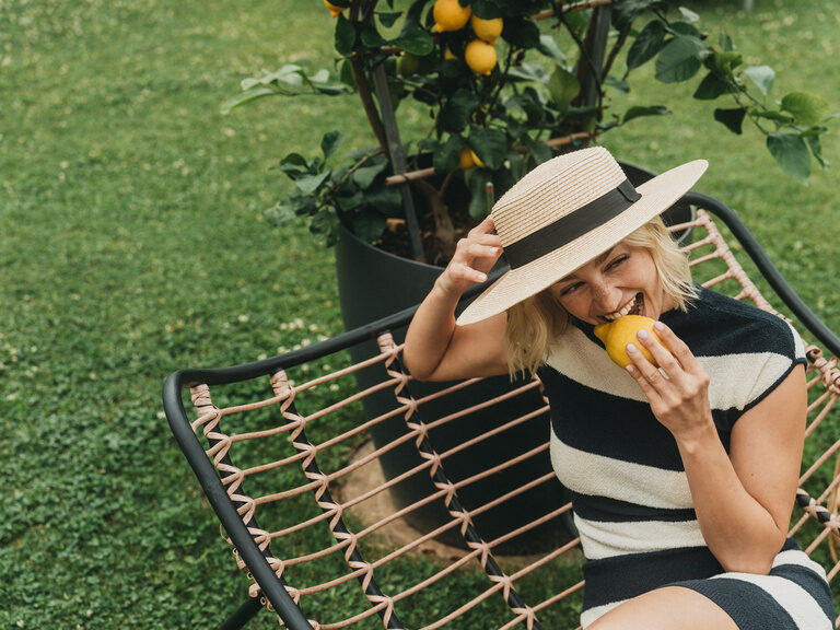 Eine Frau beisst spielhaft in eine Zitrone.