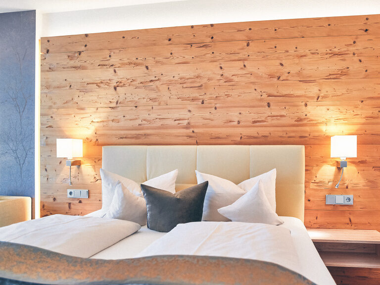 Doppelbett mit kuscheligen Kissen dekoriert.