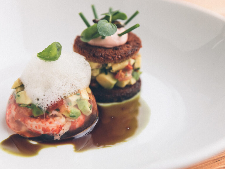 Detailaufnahme eines Gerichts das wie zwei Türme gestapelt auf dem Teller liegt.