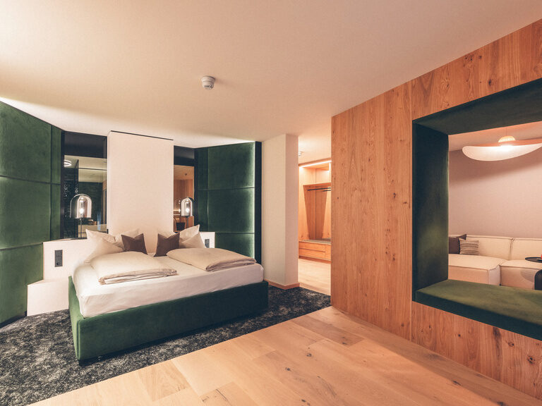 Grünes Doppelbett mit Zugang zur gemütlichen Leseecke / Sitzlounge in der Wald Spa Suite-73 im Hotel Eibl-Brunner.