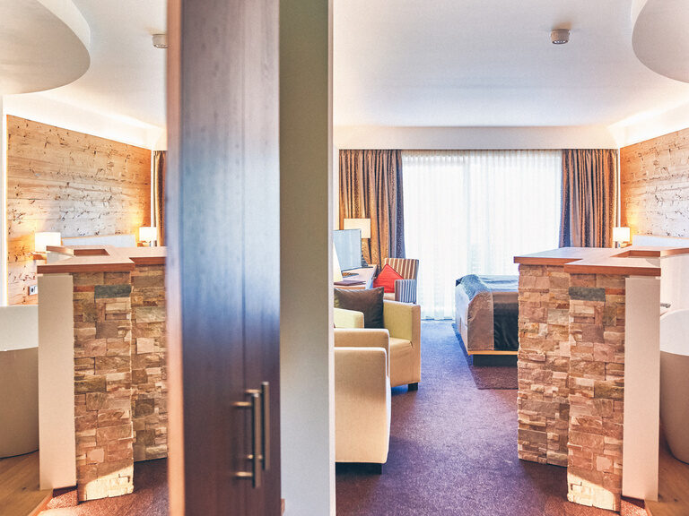 Doppelzimmer Arber mit Blick auf das Doppelbett und die Abtrennung zur im Zimmer stehenden Badewanne.