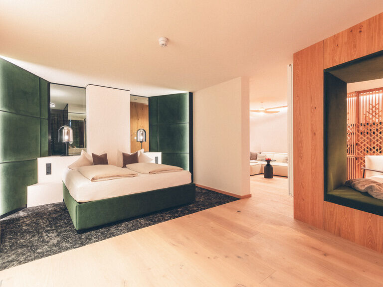 Hotel Doppelzimmer mit Leseecke und grünem Bett im Hotel Eibl-Brunner.