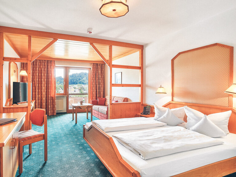 Familienappartement im Stammhaus des Hotel. Gemütliches Bett, Schreibtisch, Sitzecke mit Fernseher und Zugang zum Balkon.