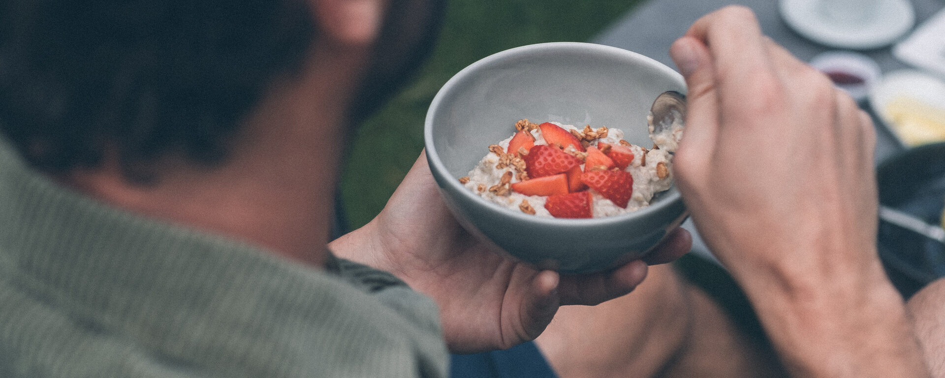 Detailaufnahme einer Müslischüssel mit Erdbeeren die von einem Gast im Hotelgarten des Hotel Eibl-Brunner gegessen wird.