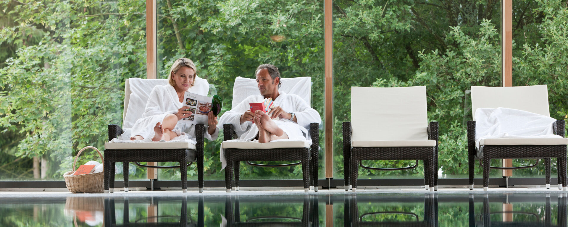 Ein Gästepaar liegt auf den Liegen im Innenbereich der Wasserwelt im Hotel Eibl-Brunner und liest ein Buch.