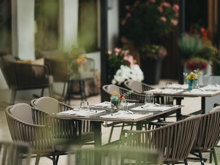 Auf der Terrasse des Hotels Eibl-Brunner warten gedeckte Tische auf die Restaurantgäste.