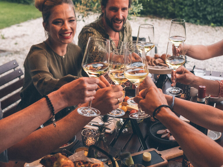 Fröhliches Anstoßen in einer gemütlichen Runde mit Essen und guter Laune im Hotelgarten des Hotel Eibl-Brunner