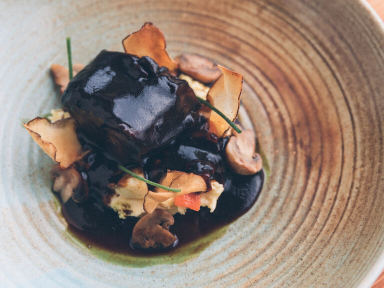 Geschmortes Wildfleisch garniert mit Trüffel und dunkler Jus.