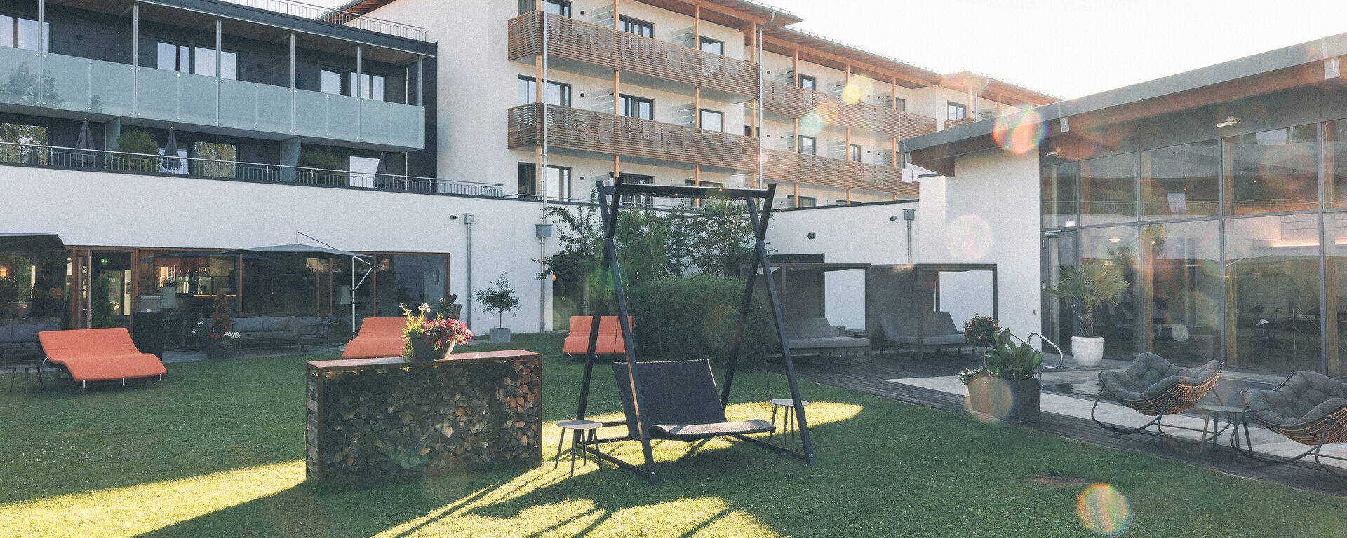 Hotelgarten mit Sonnenliegen und gemütlicher Hollywoodschaukel im Sommer.