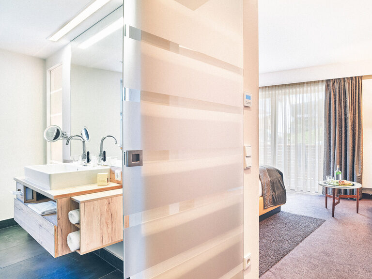 Eingangsbereich des Hotelzimmers mit Blick in das Bad und auf den Schlaf-Wohnbereich.