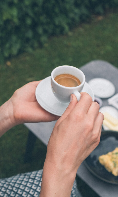 Gäste sitzen im Garten des Hotel Eibl-Brunner und trinken Kaffe zum Frühstück.