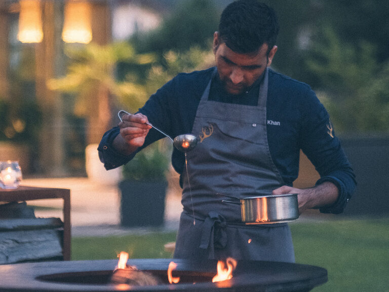 Koch an Feuerstelle im Hotelgarten von Eibl-Brunner.