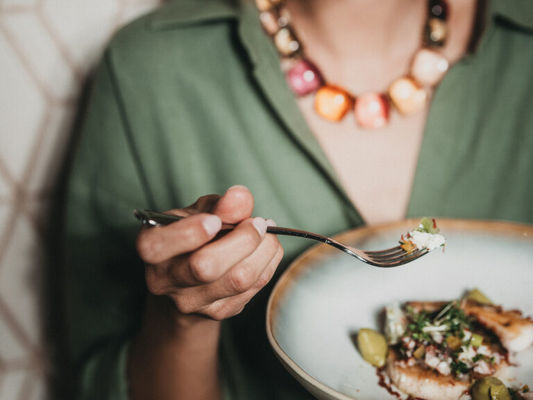 Eine junge Frau mit einem leckeren Gericht aus der Küche des Hotel Eibl-Brunner