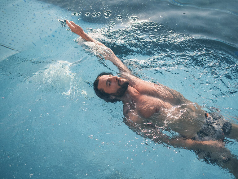 Ein Badegast beim Rückenschwimmen im Hotelpool des Hotel Eibl-Brunner.
