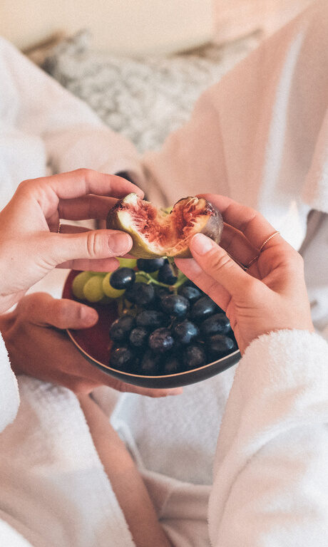 Detailaufnahme von einer kleinen Obstschüssel die von Gästen geteilt wird. Darin sind Weintrauben und Feigen.