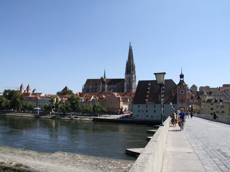 Ein Bild vom Altstadtteil der Stadt Regensburg, auf dem der Dom und die Donau zu sehen ist.