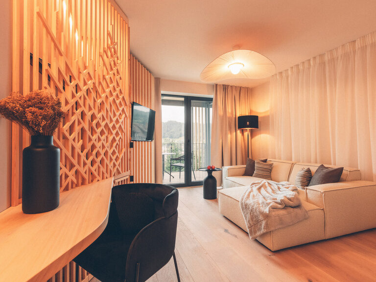 Eine gemütlcihe Sitzecke mit Blick auf den Balkon, daneben ein Schreibtisch im Wald Spa Studio im Hotel Eibl-Brunner.