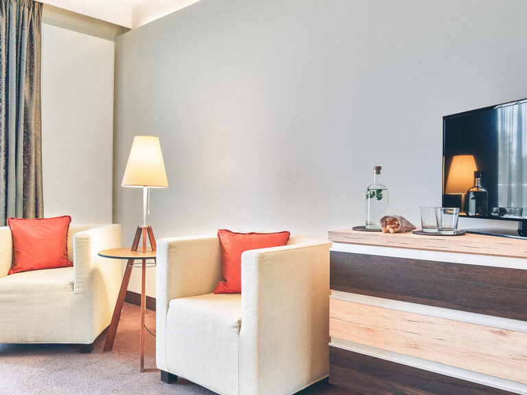 Gemütliche Sitzecke neben dem Fernseher und gegenüber des Bettes im Dopplezimmer Falkenstein im Hotel Eibl-Brunner.