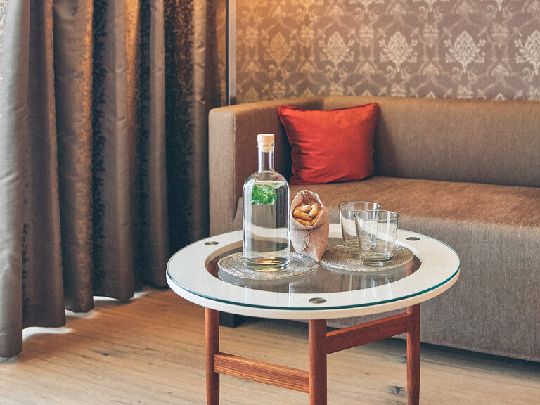 Gemütliche Sitzecke mit Tisch und Wasser im Doppelzimmer des Hotel Eibl-Brunner.