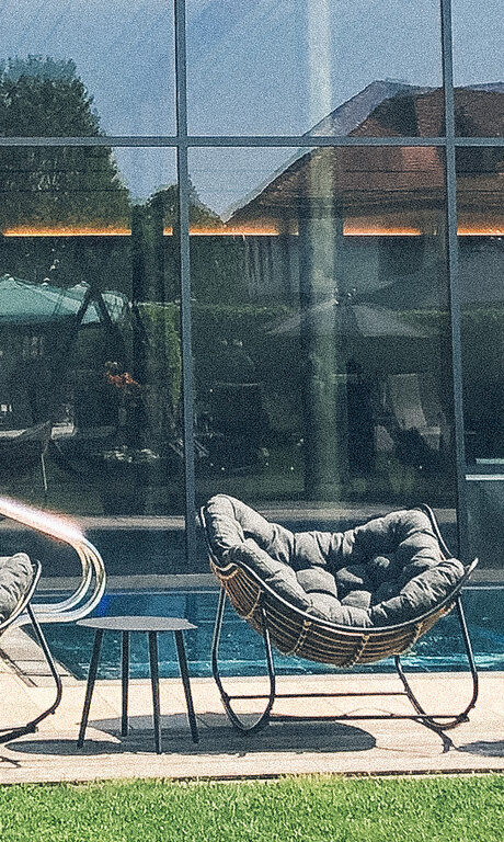 Zwei Stühle beim Außenpool, mit einem Platz an der Sonne des Hotelpools des Wellnesshotels Eibl-Brunner