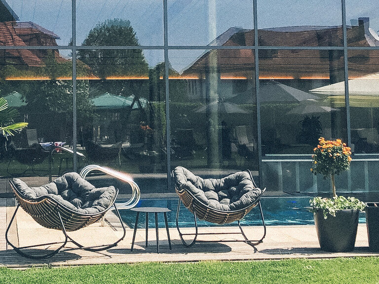 Zwei Stühle beim Außenpool, mit einem Platz an der Sonne des Hotelpools des Wellnesshotels Eibl-Brunner