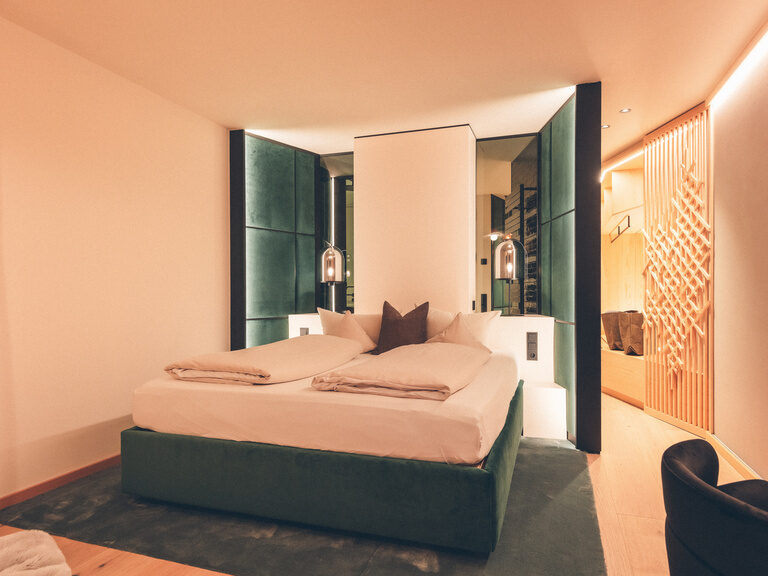 Gemütliches Doppelbett in der Wald Lounge, Ambientelicht im Gang und neben dem Bett.
