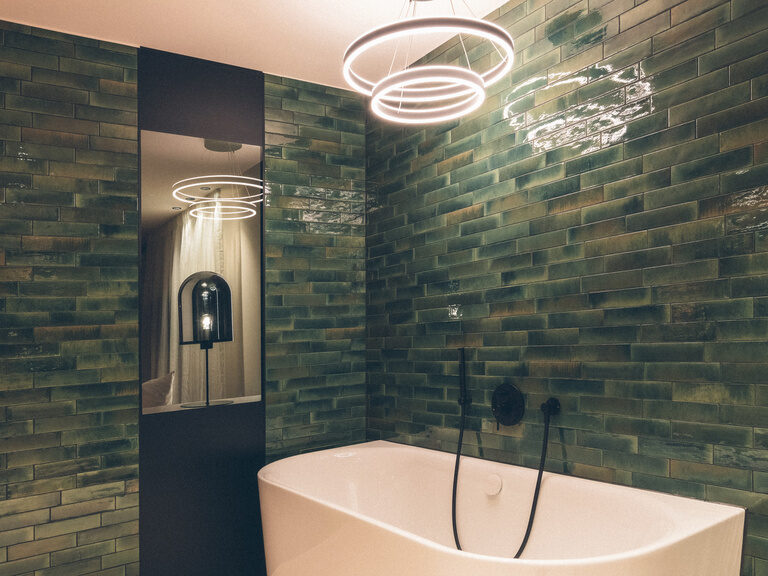 Wald Suite mit grünen Fliesen hinter der freistehenden Badewanne im offenen Badezimmer.