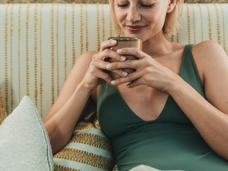 Eine junge Frau entspannt im Hotel Eibl-Brunner an einem gemütlichen Platz mit einer Tasse Tee