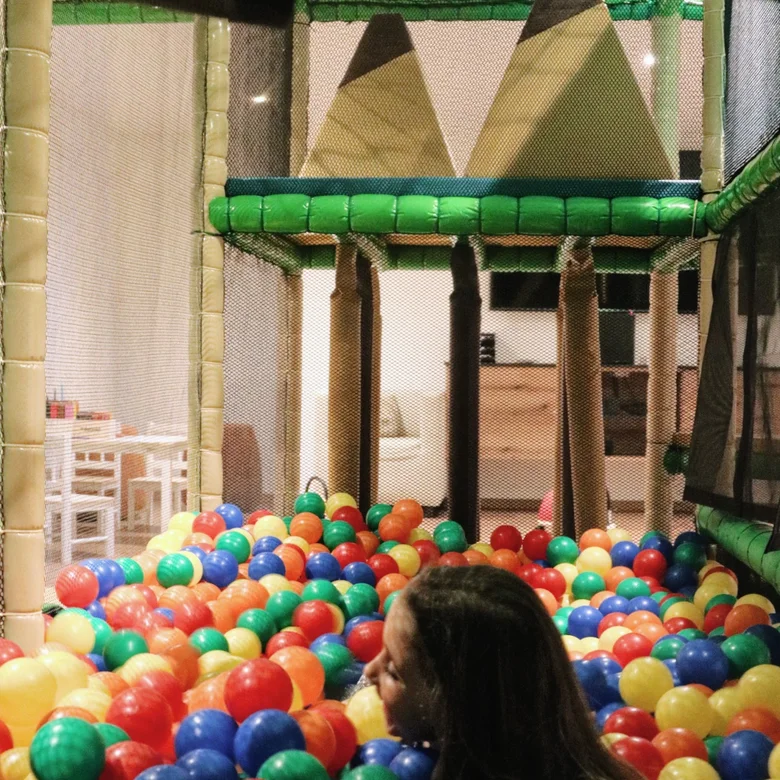 Kind spielt in einem bunten Bällebad in einer Indoor-Spielanlage