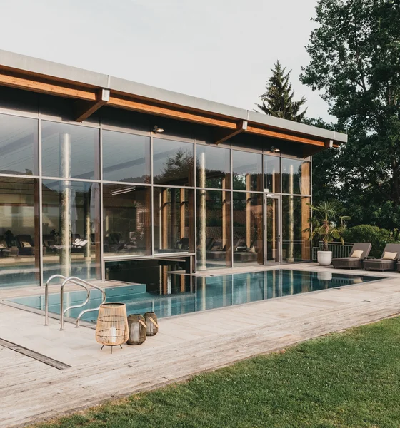 Moderner Poolbereich mit Liegestühlen und großen Glasfenstern an einem sonnigen Tag